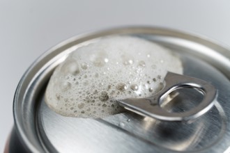Close-up detail of a beer can with foam on a white background with space for text
