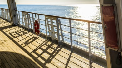 Empty wooden deck and railing with a life ring hanging on the rail on a passenger boat or cruise