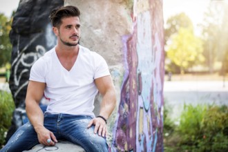 Handsome fit man in white t-shirt outdoor in city setting, looking away