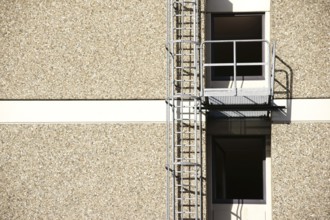 A fire escape on the side of a residential building casts a shadow