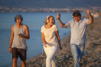 Excited friends outdoor. Young people relaxing and having fun listening to music in headphones
