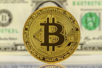 Bitcoin with dollar bill in the background