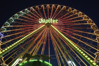Ferris wheel illuminated at night, perspective, bright lights, many colours, funfair in Bad