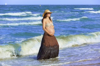 Pregnant woman on the beach playing with waves