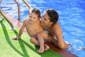 Happy mother and baby daughter girl at swimming pool in summer vacation