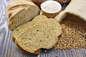 Slices of buckwheat bread, a bag of buckwheat, buckwheat flour in a bowl on a wooden boards