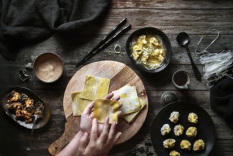Top view of anonymous woman preparing wonton soup on a wooden table