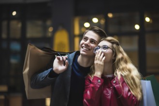 Beautiful couple with shopping bags is talking and smiling while doing shopping in the mall focus