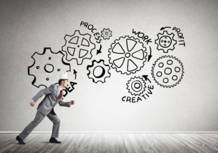 Young handsome businessman wearing white paper crown running and gear mechanism on wall