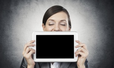 Businesswoman holding tablet computer with blank screen. Beautiful woman with closed eyes showing