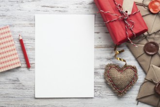 Flat lay composition with handmade fabric heart and gift box. Blank sheet of white paper on wooden