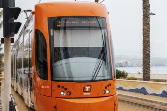 Alicante, Spain, October 14, 2023: Orange streetcar running along the promenade between Alicante