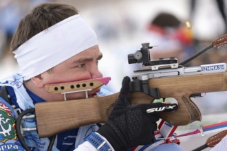Close-up view of sportsman biathlete aims rifle shooting prone position. Biathlete Andrey Krutov in
