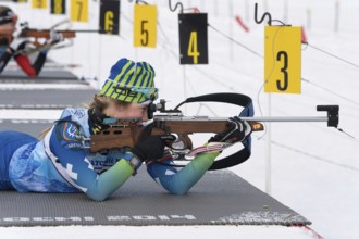 Sportswoman biathlete Anastasia Legostaeva rifle shooting in prone position. Biathlete in shooting