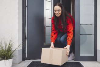 Cheerful young woman excited over a package she just received. Woman getting her christmas gift in