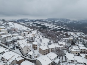Aerial view of snow-covered houses and trees in bore, a small village nestled in the hills