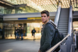 Profile shot of handsome young man inside train station looking at camera