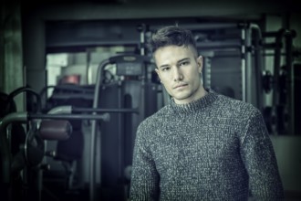 Handsome white asian young man wearing grey sweater, standing indoor in dark place