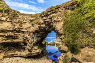 Small puddle of water in an arch. Coastal rocks formed a picturesque arch of sandstone. Great Ocean