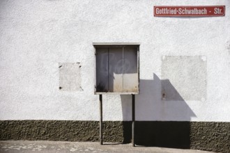 A vintage wooden display case stands on the façade of a building on the wall of which a cigarette