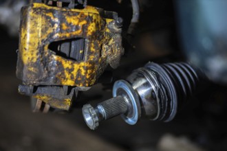 Close-up of a rusty brake caliper and mechanical components of a vehicle