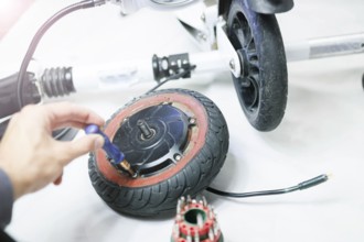 Hand working with a screwdriver on a wheel, indicating repair or assembly