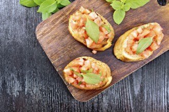 Bruschetta with tomatoes and basil on a dark wooden background from above