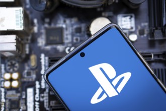 Person holding cellphone with logo of video gaming platform PlayStation Network (PSN) in front of