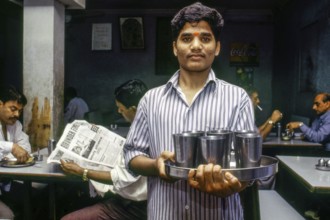 Waiter serving drinking water steel glasses, Udipi restaurant, Mumbai, Maharashtra, India, Asia