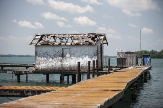 A weathered dock and shed sit along on the Detroit River along the shoreline of Southwestern
