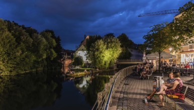 Germany, 07 26 2018: Tourists and locals sitting at the banks of the Pegnitz river, Europe