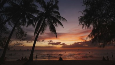 Silhouetted people and palms near sea. Sunset at tropical White beach, Boracay island, Philippines,