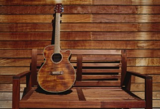 Acoustic brown guitar in a wooden stripes wooden wall monochromatic