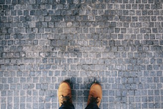 Male feet in brown boots stand on the cobblestones. Close-up.