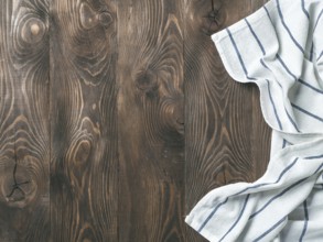 View from above on brown wooden table with linen kitchen towel or textile napkin. Blue tablecloth