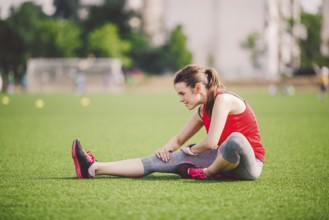 Theme sport and health. Young beautiful Caucasian woman sitting doing warm-up, warming up muscles,