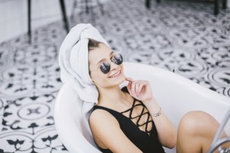 Young caucasian woman with towel on head and sunglasses getting spa treatment in a beauty salon,