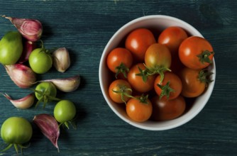 Tomatoes on the background. Tomatoes, garlic on a wooden surface. View from above. Fresh vegetables