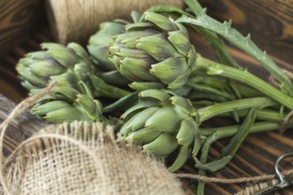 Two artichoke bouquets on kitchen table among some kitchen items. Top view