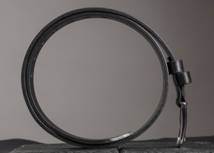 Leather belt twisted into a circle on a grey background
