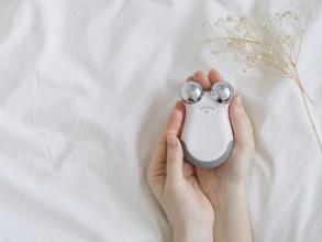 Microcurrent concept. Face massager with micro currents for home use and skincare on white bed.