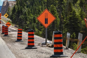 Paved surface ends ahead orange sign, Temporary condition road signs barrels, warning symbols, on