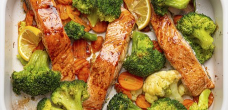 Top view close up of healthy baked fish salmon steaks, broccoli, cauliflower, carrot in casserole