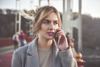 Cute smiling young woman talking on phone standing on the bride. Close up portrait