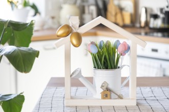 Key and tiny house of cozy home with Easter decor with color eggs on table of kitchen. Building,