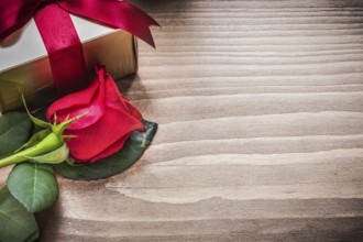 Present box with tied bow natural rose on wooden board