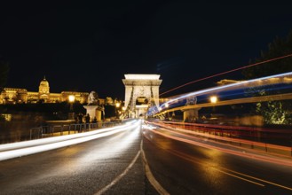 Chain Bridge and Buda castle illuminated in Budapest at night. Long exposure shot with light trails