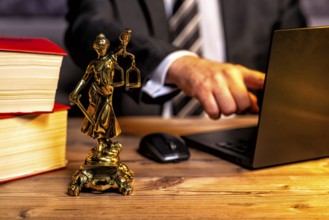 Office of a lawyer with books and a statue of Lady Justice, goddess Justitia, on the desk