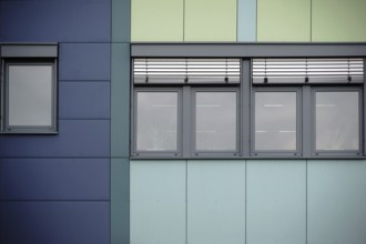 The modern façade of an office building with rows of windows and metal blinds