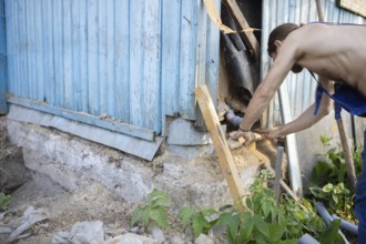 A man repairing the exterior corner of a wooden building